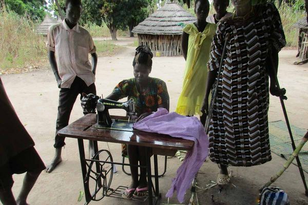Leprakranke Frau im Südsudan sitzt an der Nähmaschine